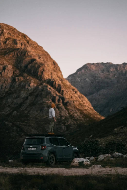 a man standing on top of a car in the mountains, by Johannes Voss, unsplash contest winner, kia soul, cape, square, profile photo