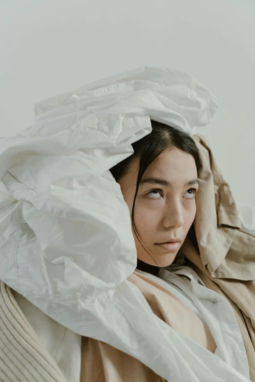 a woman sitting in a chair with a blanket over her head, inspired by Kim Tschang Yeul, trending on unsplash, visual art, model wears a puffer jacket, layered paper, fully covered in drapes, closeup portrait