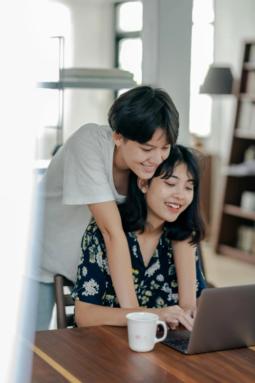 a couple of people sitting at a table with a laptop, hugging each other, jakarta, curated collections, your mom