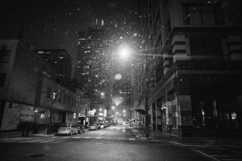 a black and white photo of a city street at night, a black and white photo, pexels, snowflakes falling, minneapolis, lowres, snowglobe