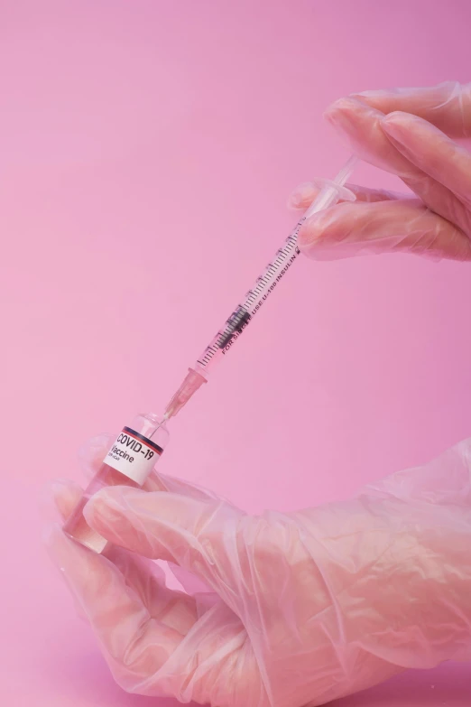 a person holding a syet in their hand, trending on pexels, plasticien, holding a syringe, pink hue, nfts, made of lab tissue