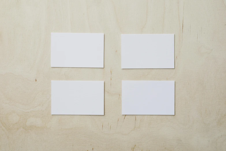 four blank white cards placed on a wooden surface, by Nick Fudge, private press, mint, 35 mm product photo”, labels, small