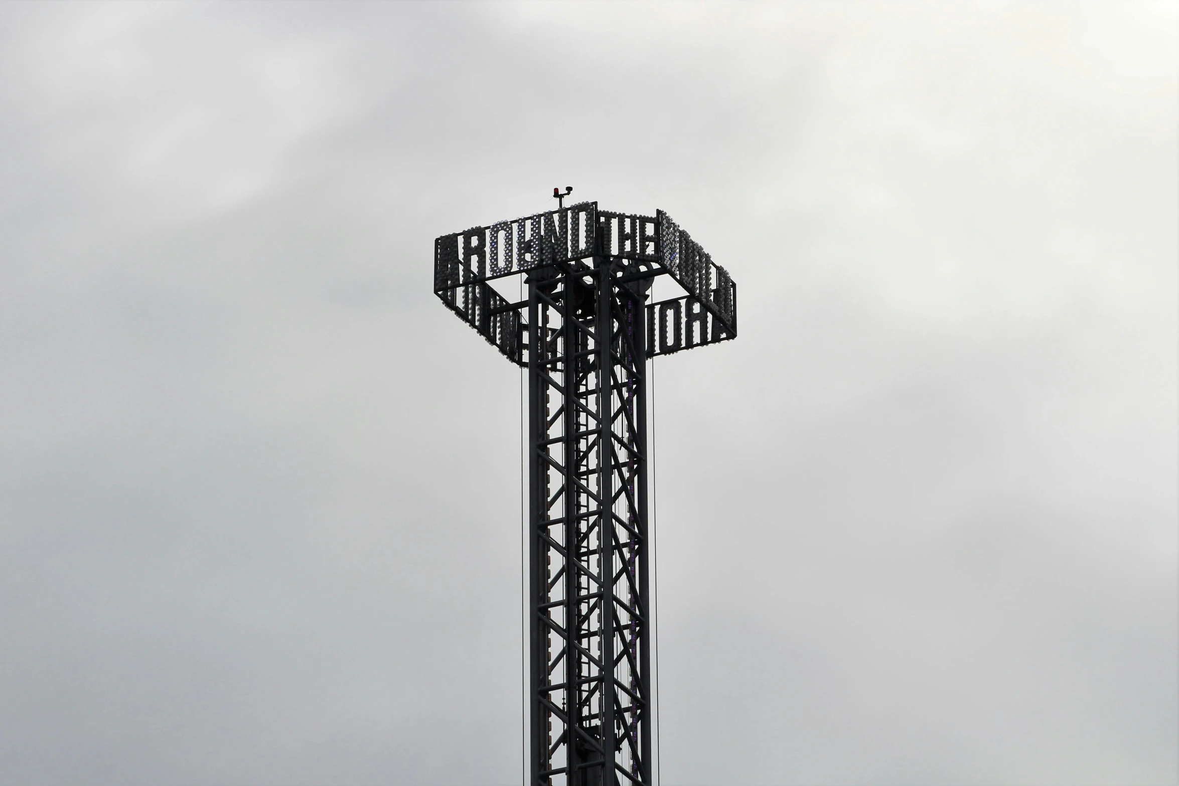 a tall tower with a cross on top of it, by Paul Bird, new sculpture, theme park, floodlight, platforms, crows