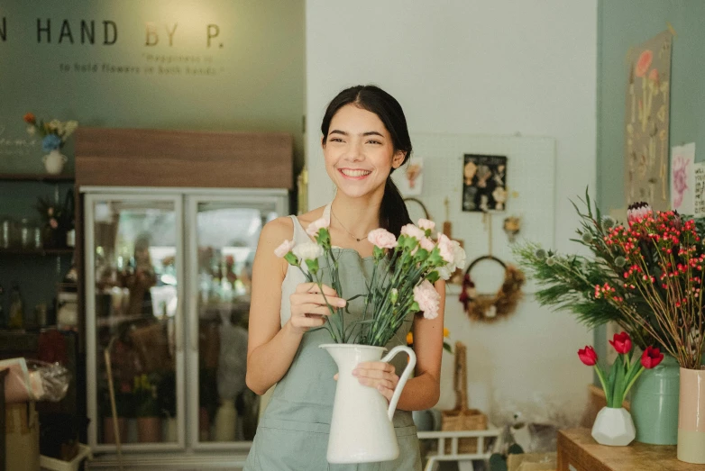 a woman holding a vase with flowers in it, customers, pokimane, smiling slightly, commercial photo