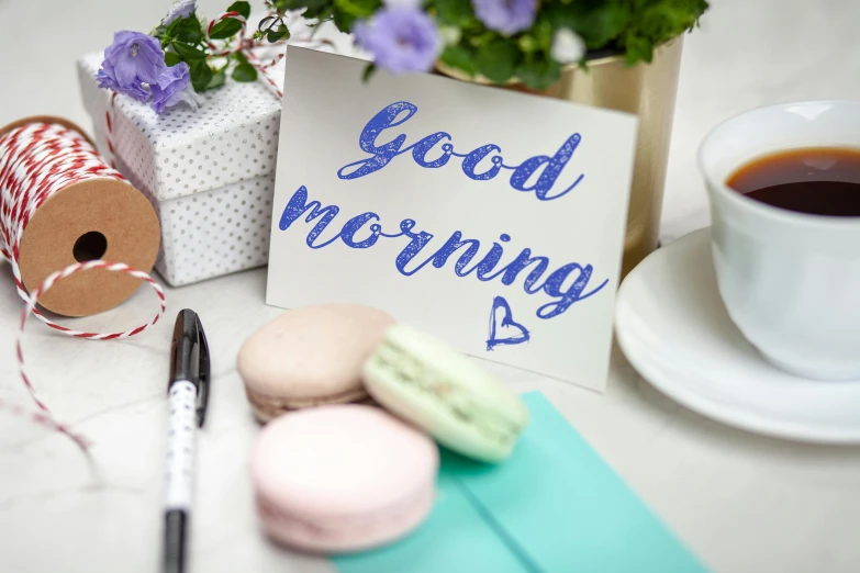 a cup of coffee and some macaroons on a table, a picture, trending on pexels, happening, “modern calligraphy art, good morning, blue and violet, whiteboards