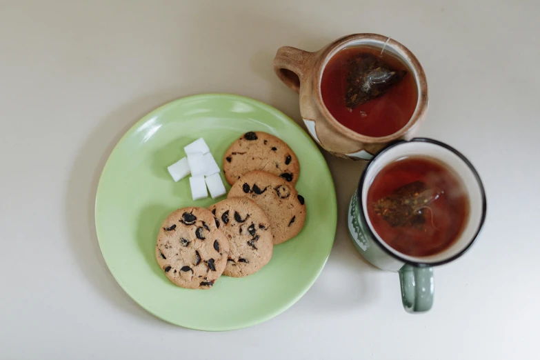 a green plate topped with cookies next to a cup of tea, inspired by Wlodzimierz Tetmajer, pexels, square, mukbang, thumbnail, 8 0 mm photo