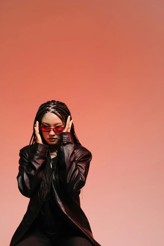 a woman sitting on a stool with her hands on her face, an album cover, inspired by Zhu Da, trending on pexels, long black braids, red sunglasses, girl in studio, concept photoset