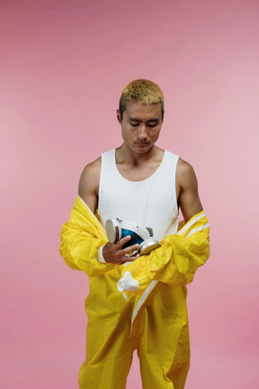 a man in a yellow rain suit holding a soccer ball, an album cover, inspired by Russell Dongjun Lu, hyperrealism, wearing a tanktop, ethnicity : japanese, non binary model, holding a bottle of arak