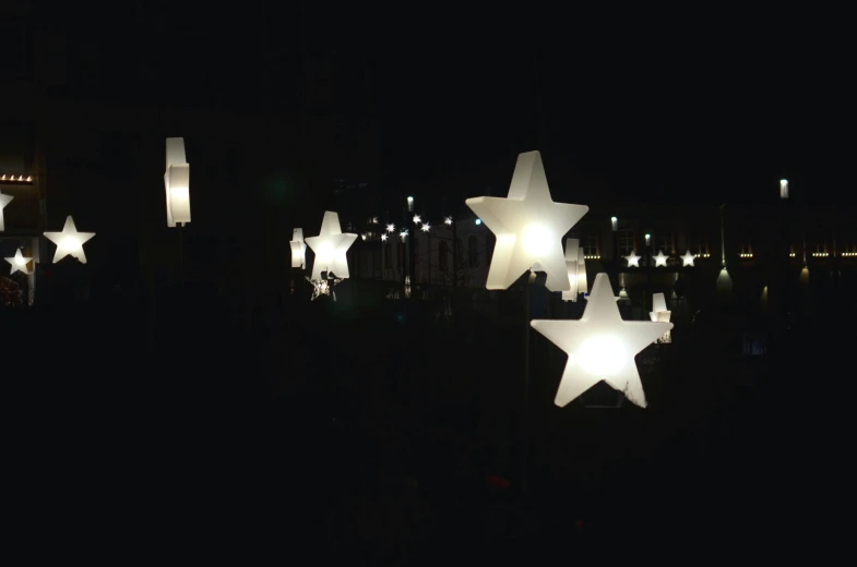 a bunch of stars are lit up in the dark, inspired by Jan Rustem, light and space, hanging lanterns, outdoor lighting, inflateble shapes, in a row