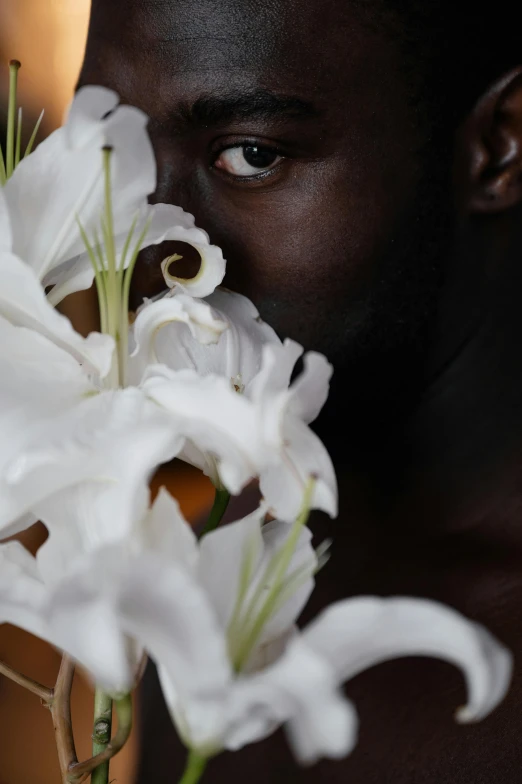 a man holding a bunch of white flowers, inspired by Robert Mapplethorpe, trending on unsplash, lupita nyong'o, ignant, big lilies, face closeup