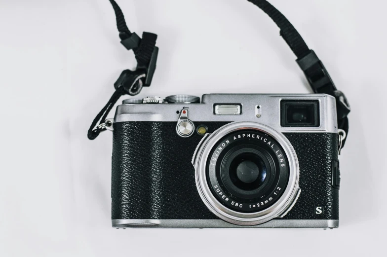 a black and silver camera on a white surface, unsplash contest winner, fujifilm x100v, fan favorite, vintage soft grainy, colored photography