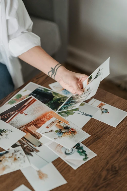 a woman sitting at a table with a bunch of photos on it, trending on pexels, platinum printing, inspect in inventory image, like small pieces, botanical photo