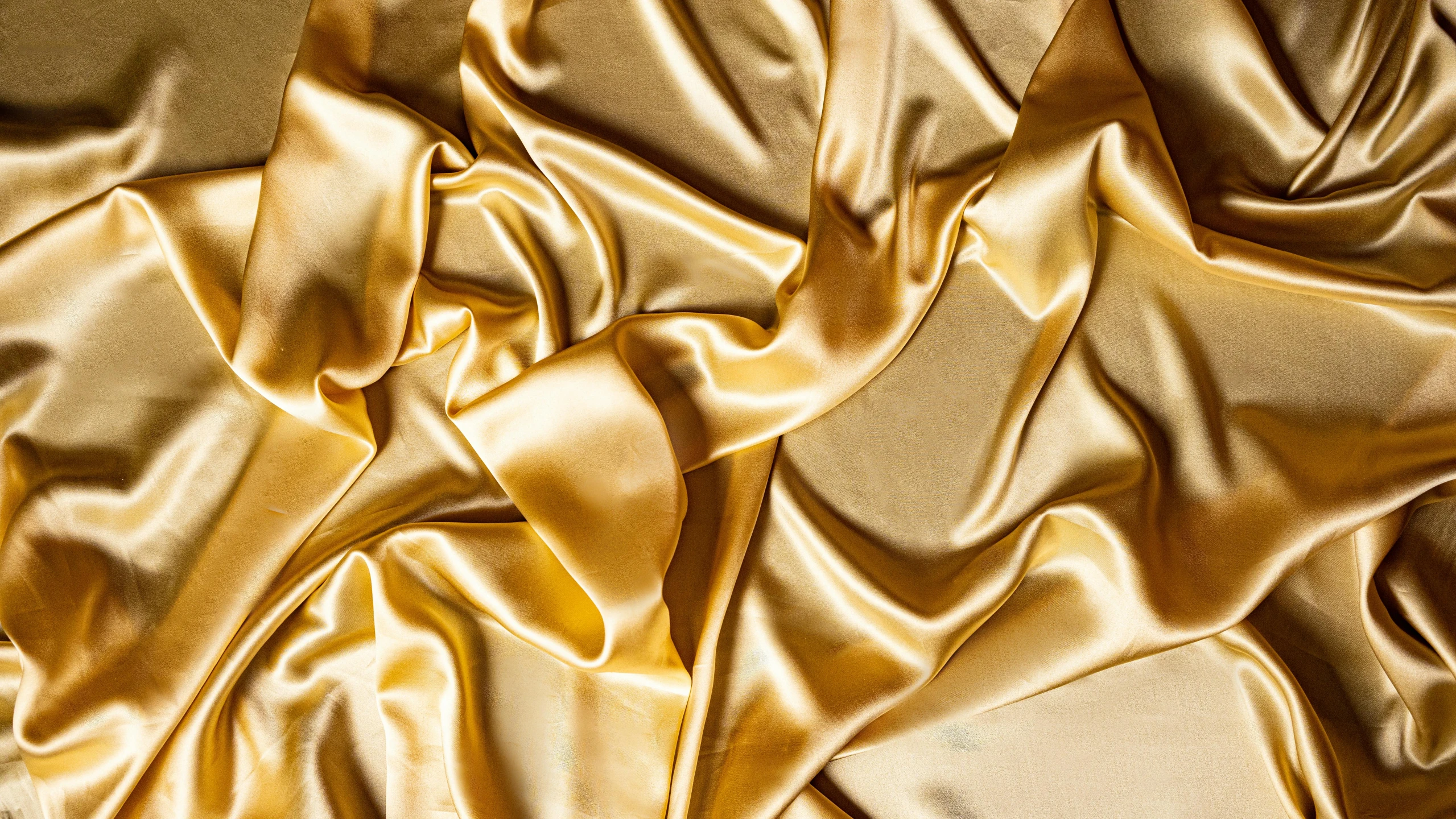 a close up of a shiny gold fabric, an album cover, by Julia Pishtar, trending on pexels, baroque, flowing silk sheets, yellow clothes, satin ribbons, sleek gold armor