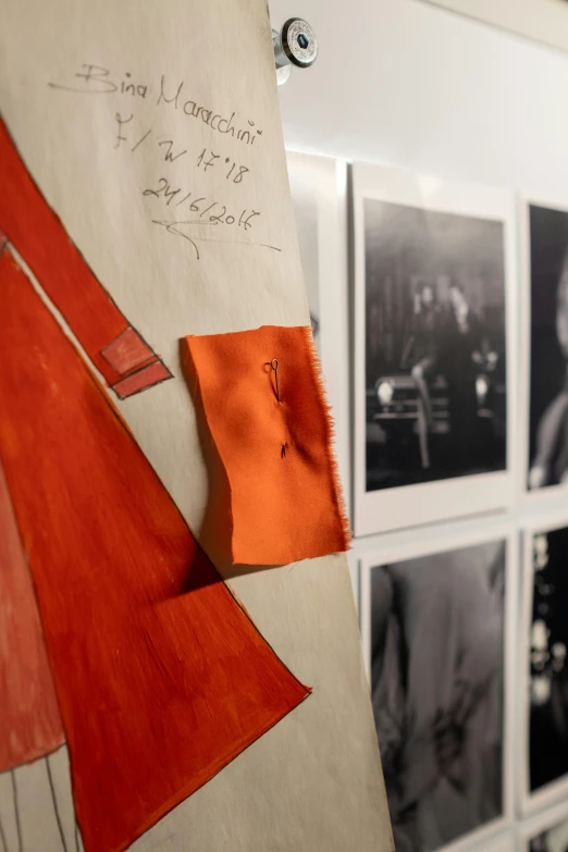 a surfboard with a piece of paper attached to it, a photo, inspired by René Burri, black and orange coat, details visible, exhibition display, grayscale photo with red dress