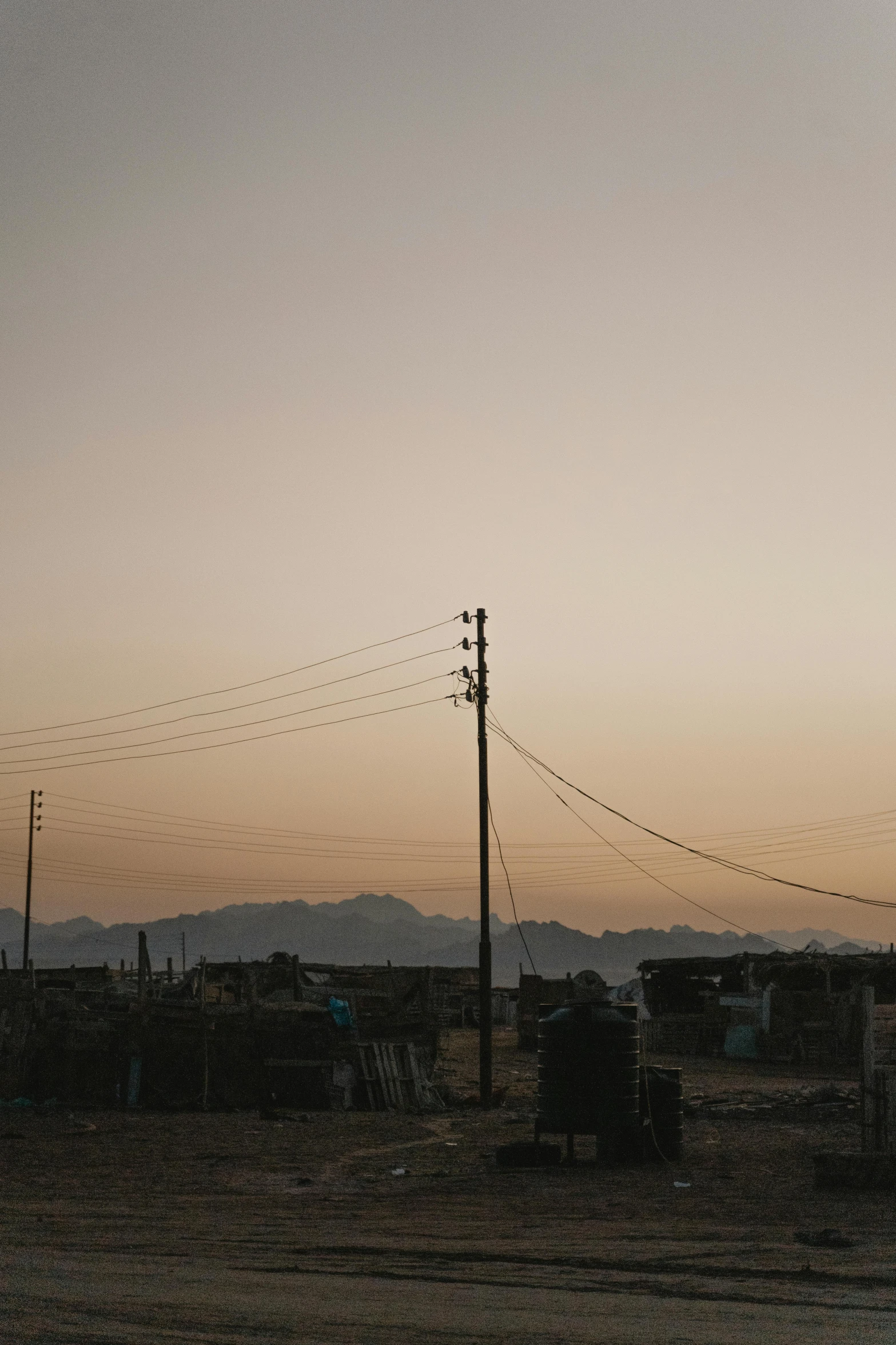 a man flying a kite on top of a sandy beach, an album cover, unsplash, distant town lights, from egypt, powerlines, shanty townships