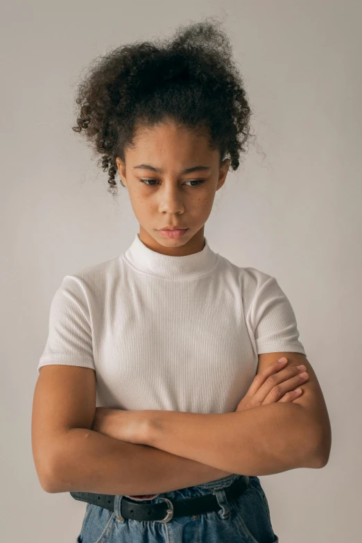 a young girl standing with her arms crossed, trending on pexels, mixed race woman, concerned, in white turtleneck shirt, wearing a t-shirt