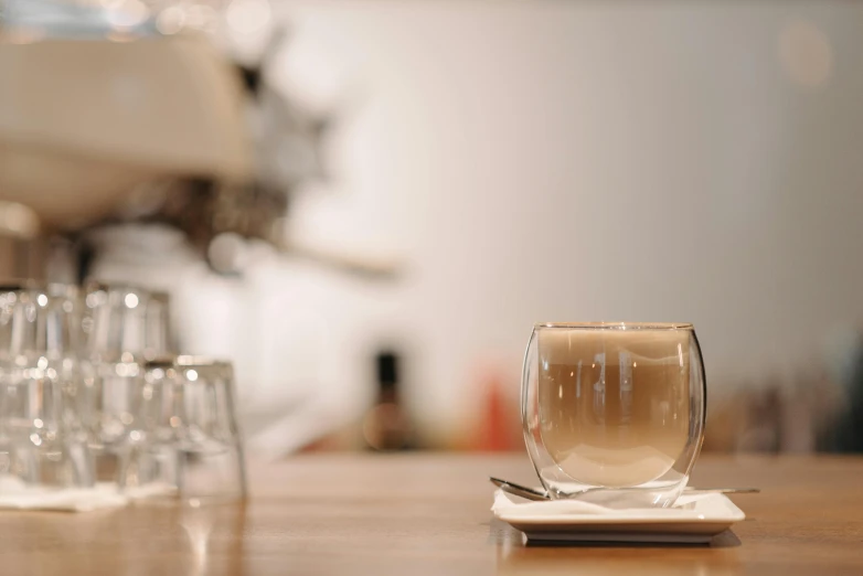 a group of wine glasses sitting on top of a wooden table, drinking a coffee, hazy water, at the counter, vanilla