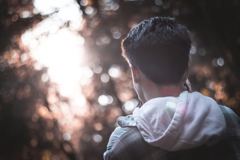 a man talking on a cell phone in the woods, a picture, trending on pexels, lovely bokeh, looking her shoulder, back - lit, male teenager