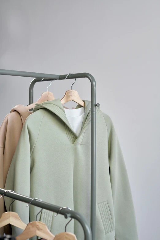 clothes hanging on a rack in a clothing store, inspired by Kanō Tan'yū, minimalism, wearing an oversized hoodie, light green, detailed product image, single subject