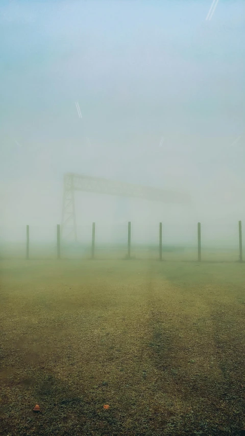 a foggy field with a soccer goal in the distance, inspired by Zhang Kechun, unsplash, conceptual art, photograph ”