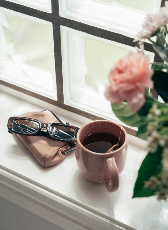 a cup of coffee and a book on a window sill, inspired by Henry O. Tanner, rose gold, woman with rose tinted glasses, square rimmed glasses, 2019 trending photo