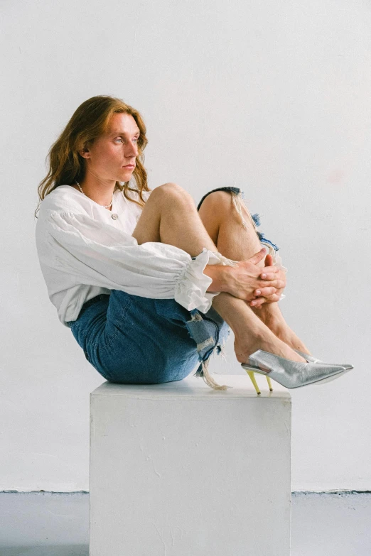 a woman sitting on top of a white box, inspired by Sarah Lucas, trending on unsplash, hyperrealism, high heels, portrait androgynous girl, shiny and metallic, wearing denim