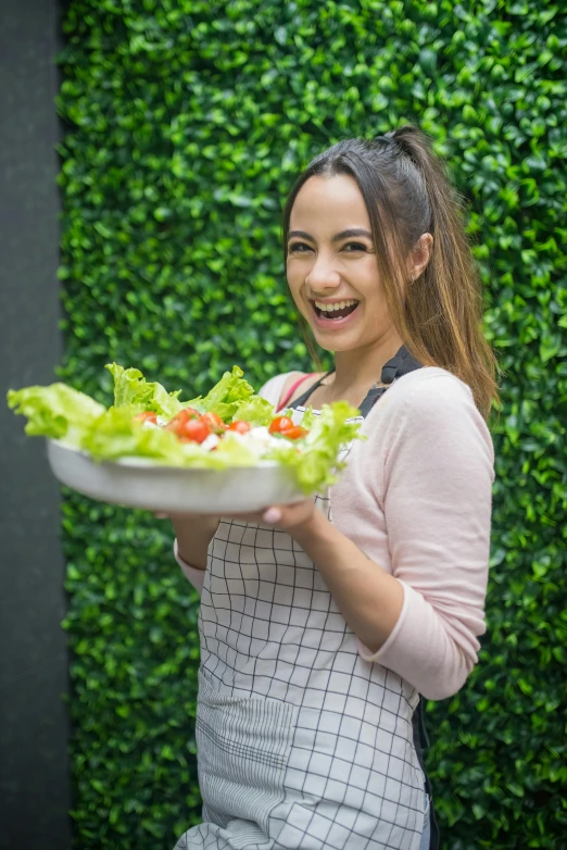 a woman in an apron holding a bowl of salad, inspired by Gina Pellón, isabela moner, happy smiling, casual, no cropping