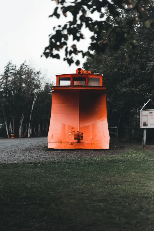 a snow plow sitting on top of a lush green field, unsplash contest winner, environmental art, orange metal ears, shipyard, slight overcast lighting, massive wide trunk