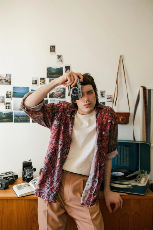 a man taking a picture of himself with a camera, a polaroid photo, inspired by Elsa Bleda, trending on pexels, visual art, declan mckenna, patterned clothing, apartment of an art student, cottagecore hippie