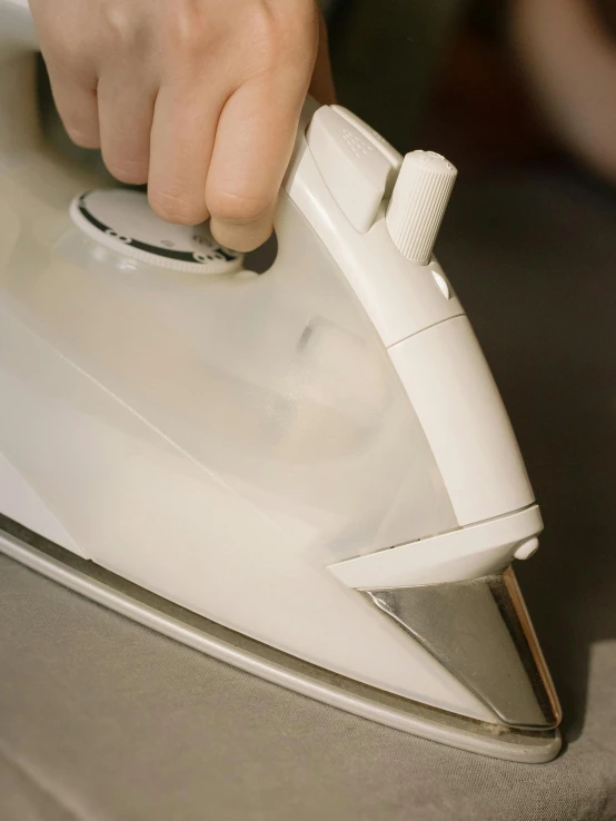 a close up of a person using an iron, by Ben Zoeller, white, angle view, close-up photograph, high angle