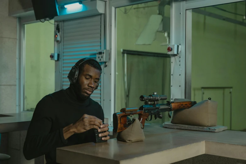 a man sitting at a table with a gun in his hand, pexels contest winner, sitting at a control center, mkbhd, ready to model, at the counter