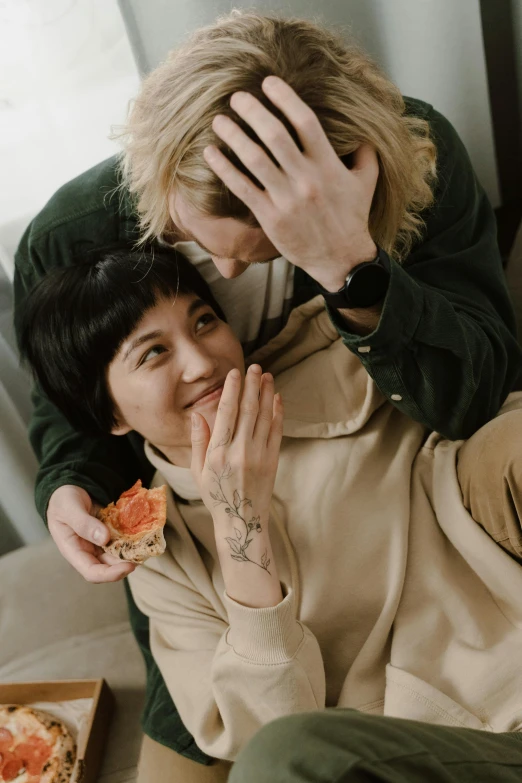 a man and a woman sitting on a couch eating pizza, trending on pexels, visual art, greeting hand on head, tatsumaki, loving embrace, she is eating a peach