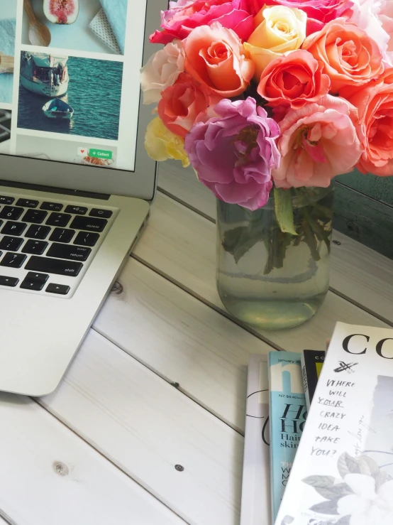 a laptop computer sitting on top of a table next to a vase of flowers, by Arabella Rankin, magazines, office background, loosely cropped, pinterest style