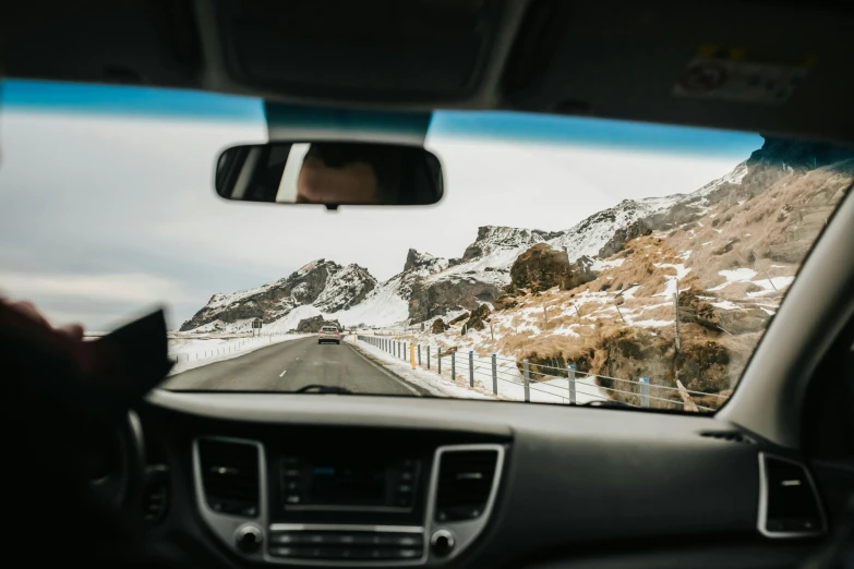 a person driving a car on a snowy road, pexels contest winner, snowy craggy sharp mountains, avatar image, view from inside, ground level shot