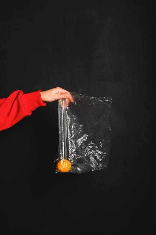 a person holding an orange in a plastic bag, smoking vessels, black backdrop, detailed product image, launching a straight ball