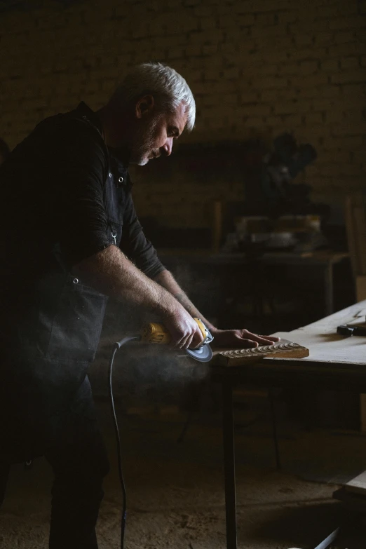 a man working on a piece of wood in a workshop, a portrait, by Peter Churcher, dusty lighting, plating, profile image, cooking it up