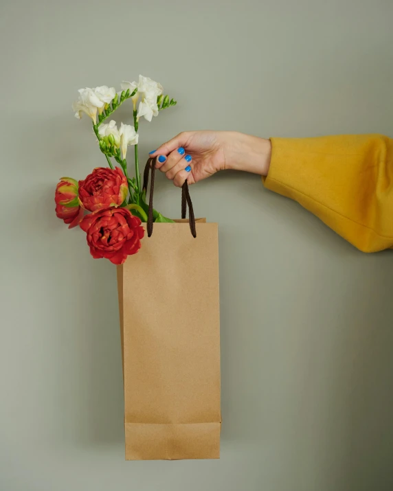 a person holding a paper bag with flowers in it, press shot, product display photograph, entertaining, stems