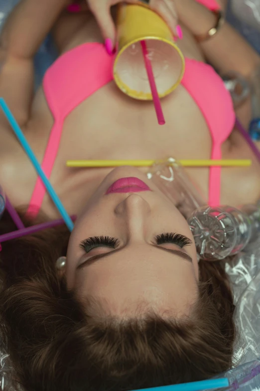 a woman in a pink bikini laying on a bed, inspired by David LaChapelle, trending on pexels, kitsch movement, vials, with a straw, gif, high angle close up shot