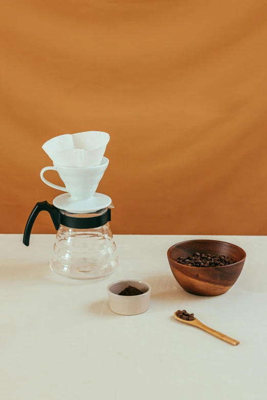 a coffee maker sitting on top of a table next to a wooden bowl, a still life, unsplash, plain background, nanae kawahara, starbucks aprons and visors, 3/4 front view