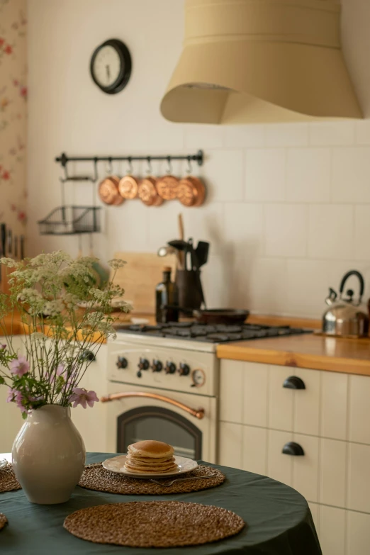 a kitchen with a green table cloth on the table, inspired by Annabel Kidston, unsplash, renaissance, ivory and copper, stove, decorated with flowers, modern studio light soft colour