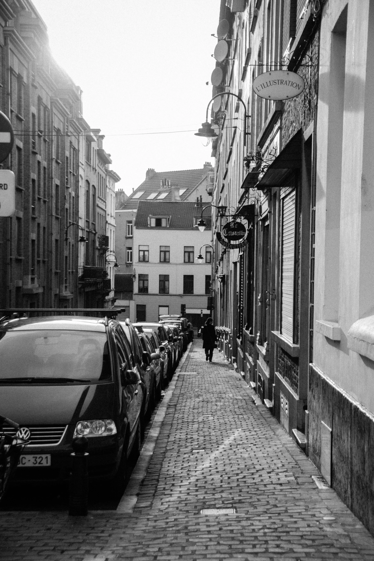 a black and white photo of a street with parked cars, renaissance, liege, narrow hallway, walking to work, street pic