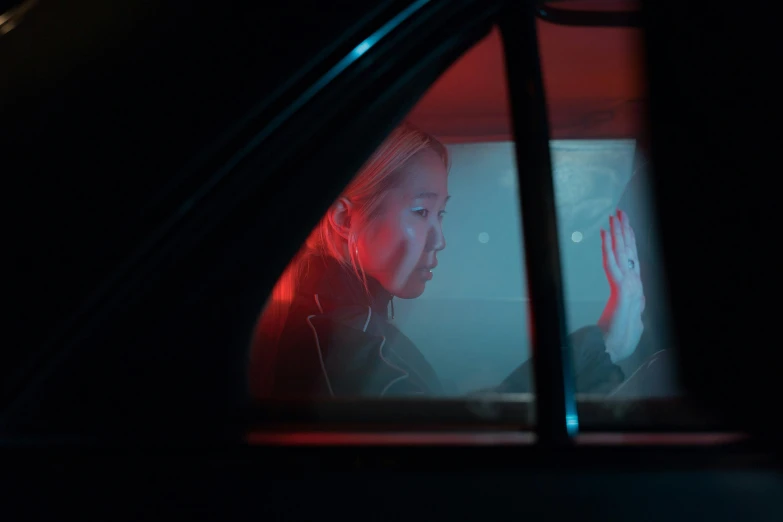 a woman sitting in the passenger seat of a car, by Adam Marczyński, photorealism, cinematic red lighting, sangsoo jeong, looking into a mirror, concerned