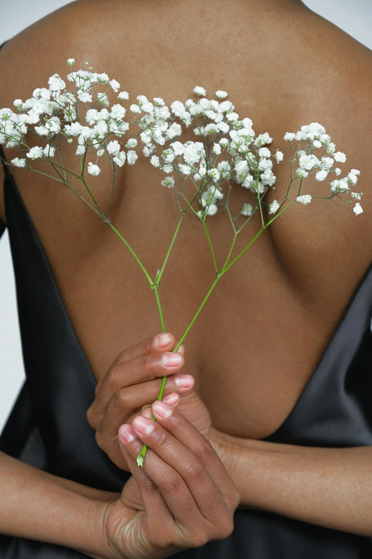 a woman in a black dress holding a bunch of flowers, inspired by Robert Mapplethorpe, aestheticism, gypsophila, wearing bra, skincare, ebony skin