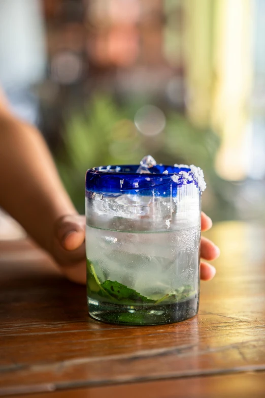 a close up of a person holding a glass of water, el dorado, indigo, handcrafted, daily specials