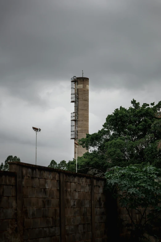 a man riding a skateboard on top of a cement wall, brutalism, chimney with smoke, mongezi ncaphayi, collapsed water tower, on a cloudy day