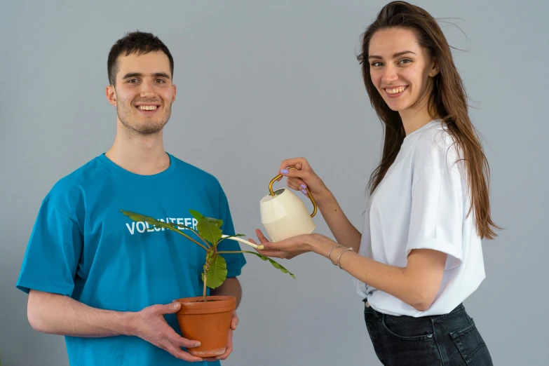 a man and a woman holding a potted plant, a photo, by Attila Meszlenyi, dressed in a white t shirt, avatar image, pouring, professional profile photo