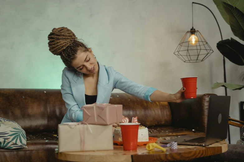 a woman sitting on top of a couch next to a coffee table, pexels contest winner, happening, birthday wrapped presents, crying and reaching with her arm, girl with messy bun hairstyle, gif