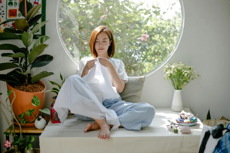 a woman sitting on top of a bed next to a window, inspired by Kim Jeong-hui, pexels contest winner, having a snack, white sleeves, avatar image, acupuncture treatment