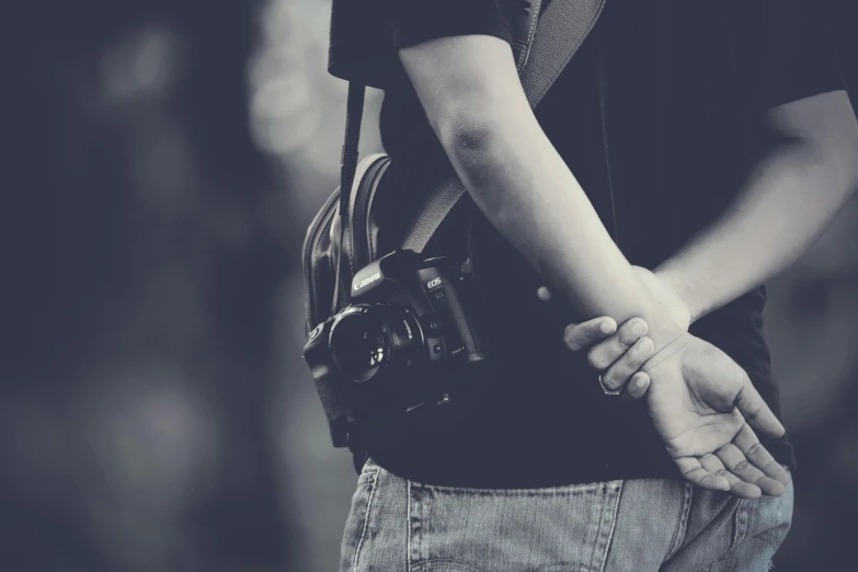 a black and white photo of a person holding a camera, holding arms on holsters, today\'s featured photograph 4k, hugging, colored photography