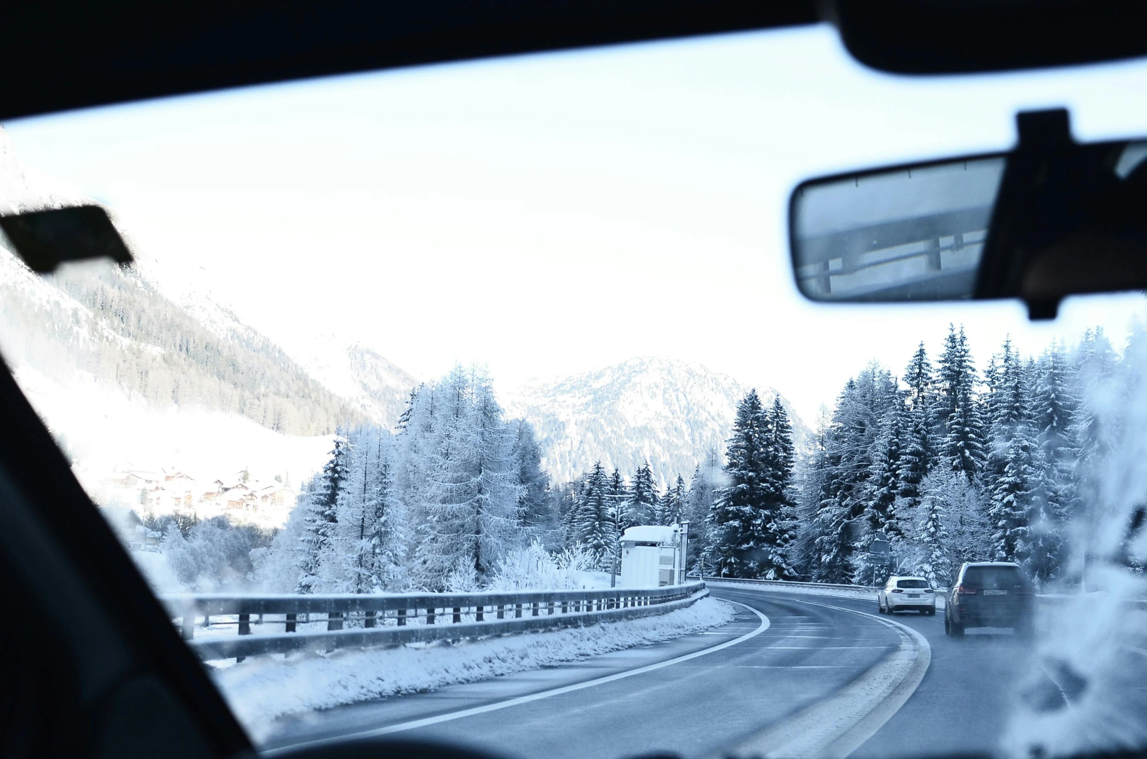 a person driving a car on a snowy road, a photo, visual art, dolomites in the background, thumbnail, brightly lit, grey